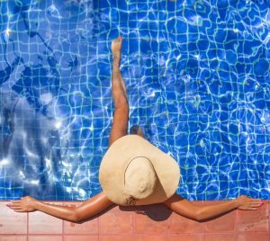 Young Slim Woman In Hat Sitting Swimming Pool