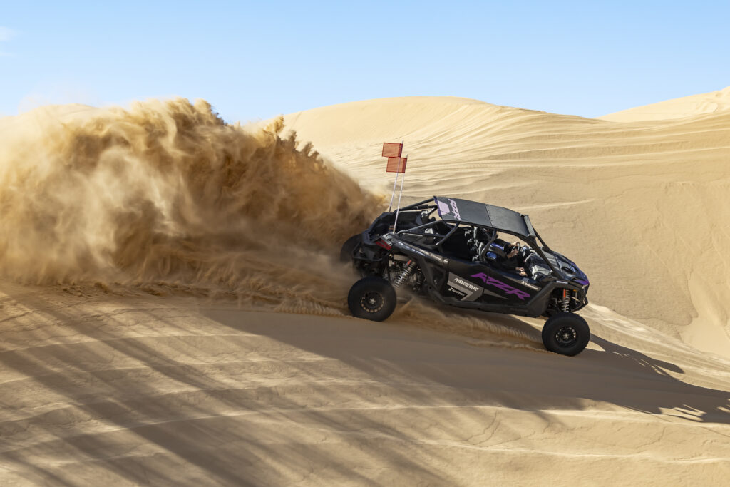 Danielle Becker on assignment with La Revista Mujer takes a hot lap in the RZR Pro R Race Replica in the dunes of Glamis with Polaris factory racing team member and winner Cayden MacCachren